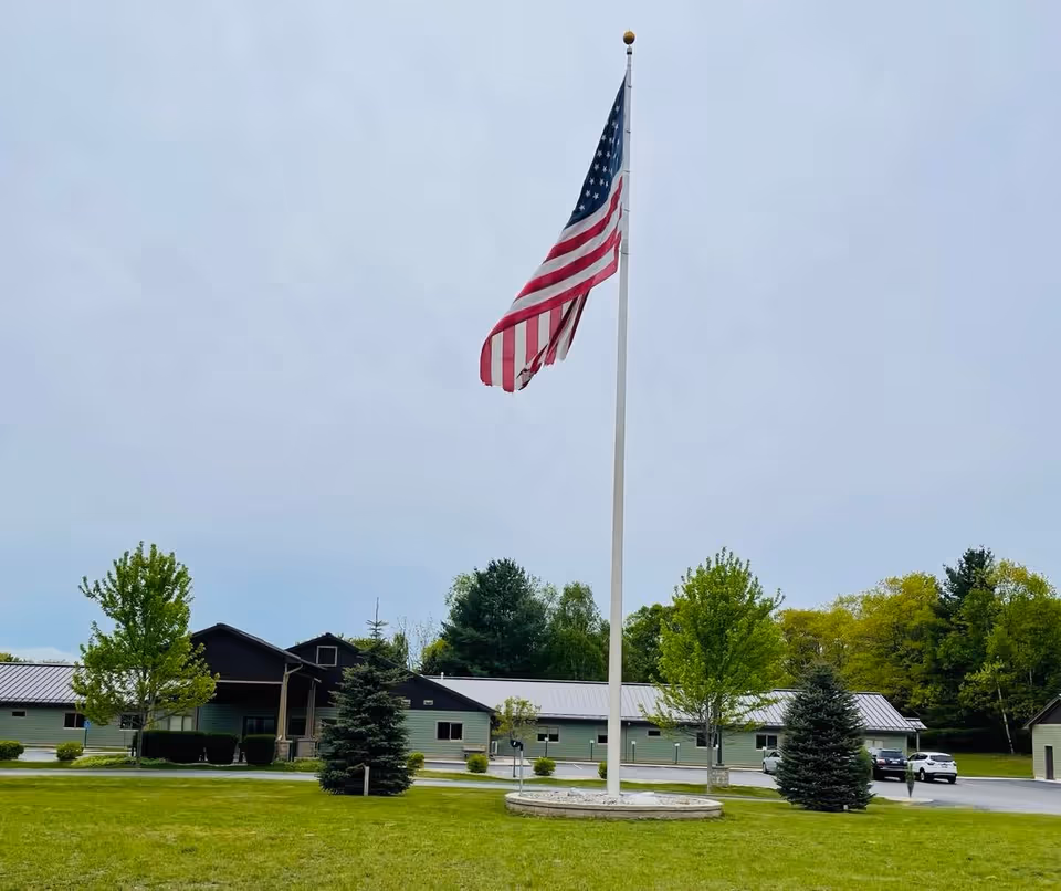 American flag on a tall flagpole in front of Culver Meadows Senior Living campus.