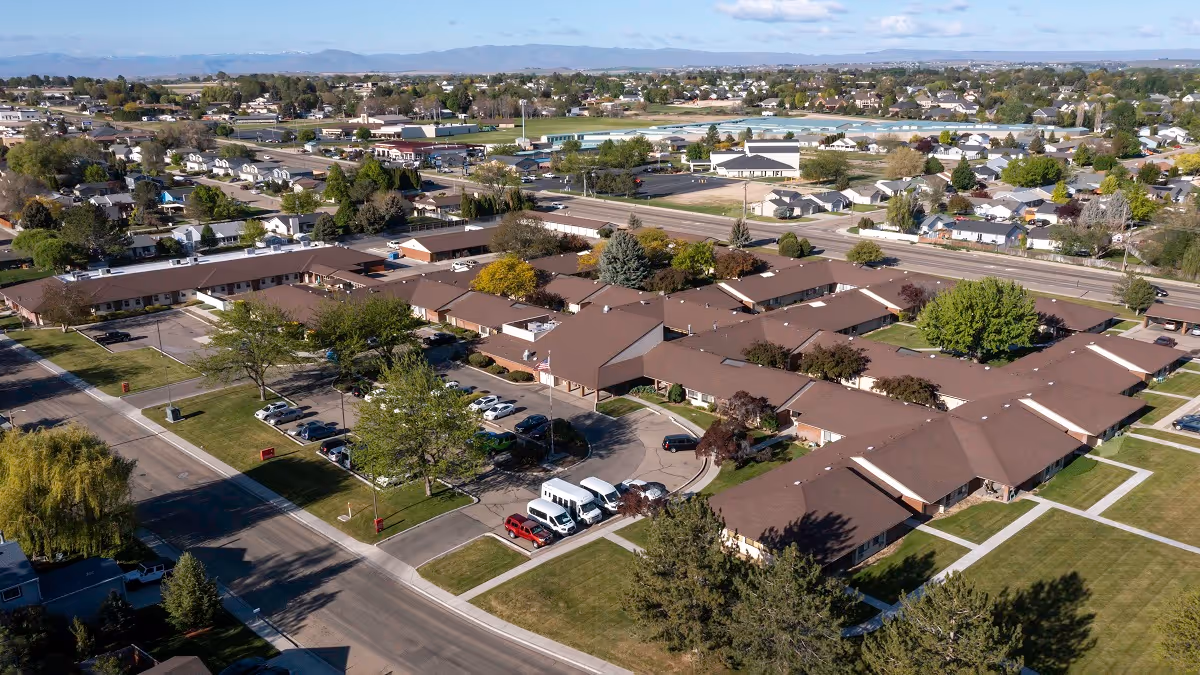 Aerial view of a brown-roofed Sunny Ridge senior living campus with parking and lawns.
