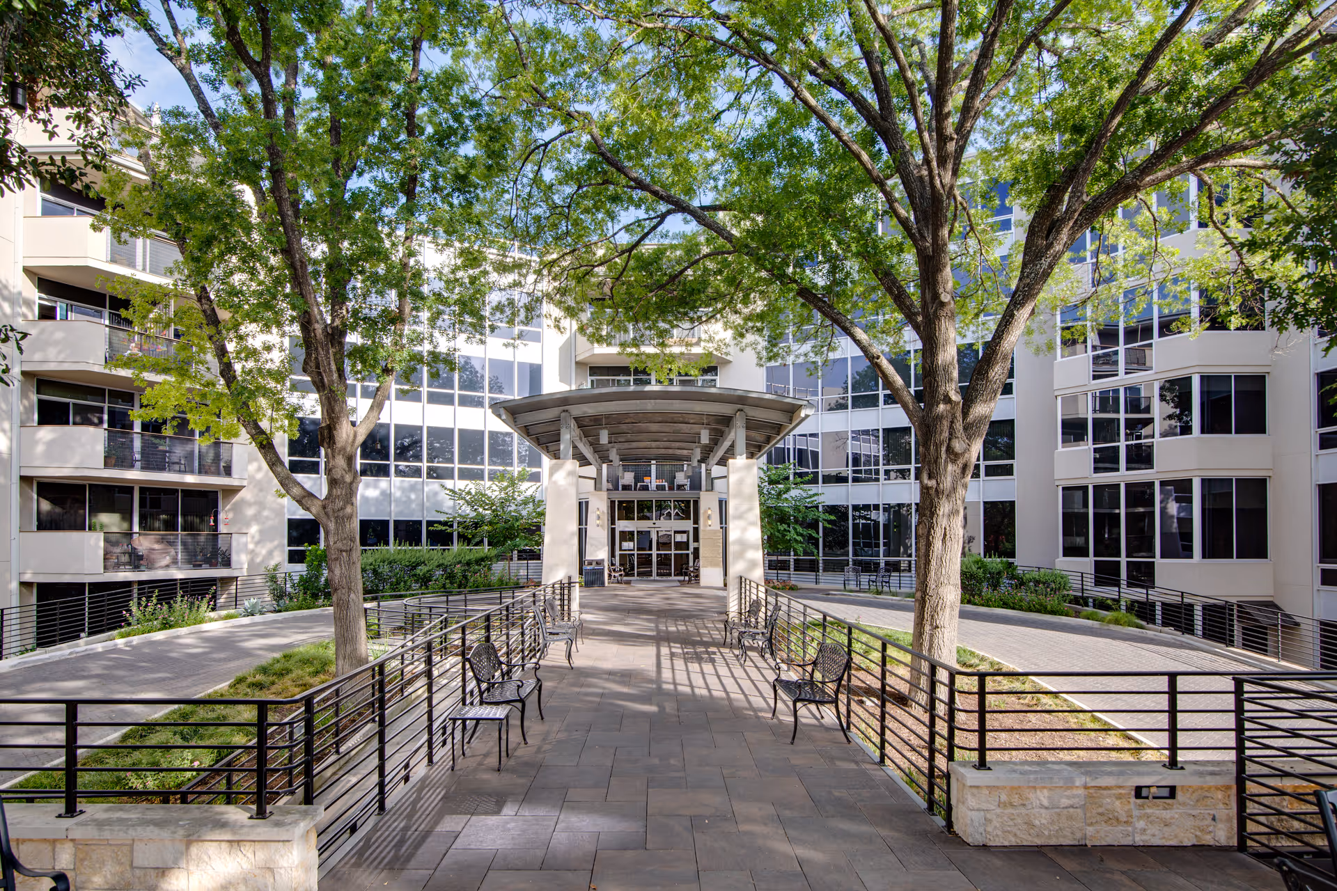 Exterior view of Westminster senior living facility with a tree-lined walkway and benches.