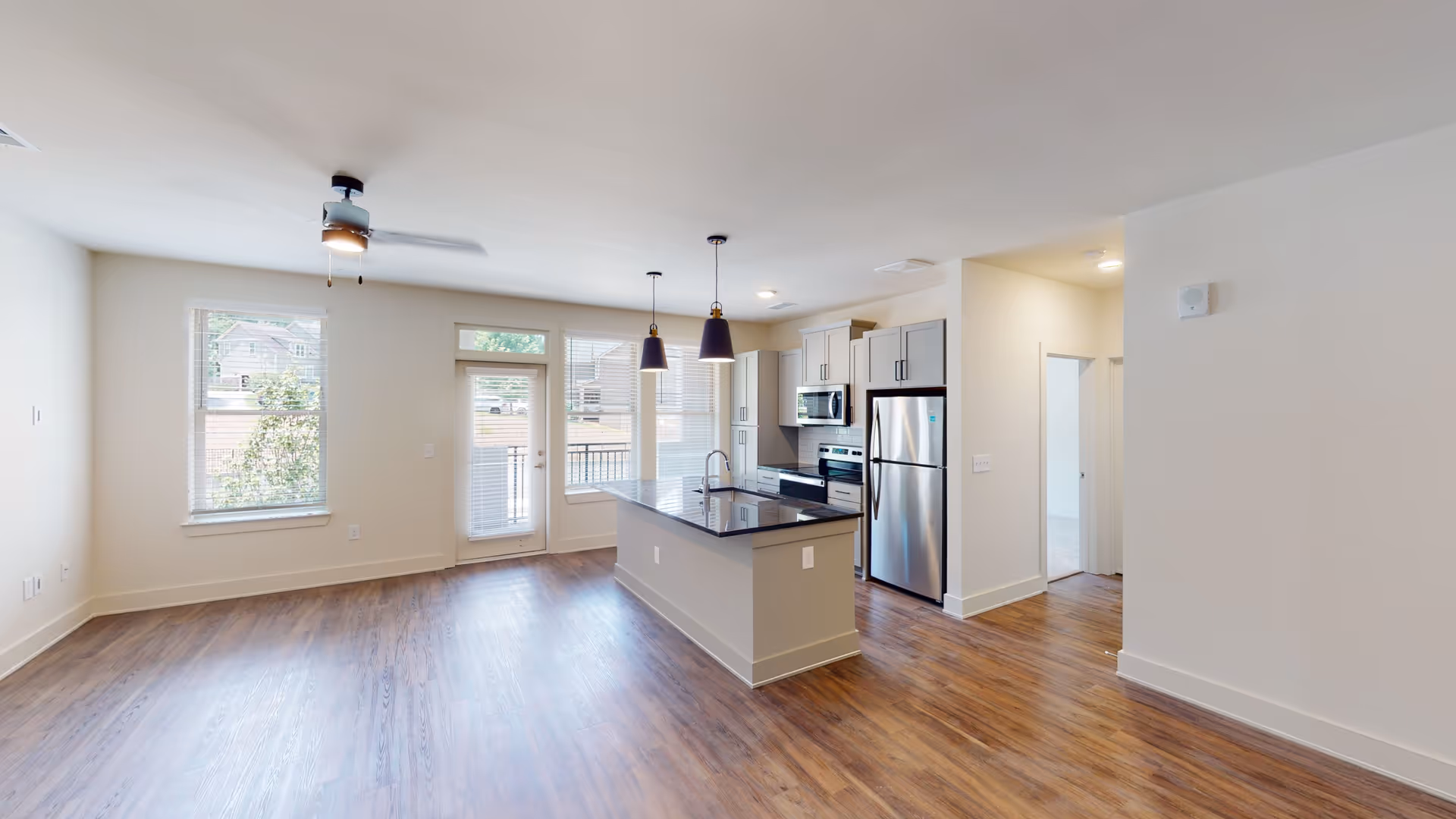 Open-concept living area featuring a kitchen island, stainless appliances, and hardwood floors.