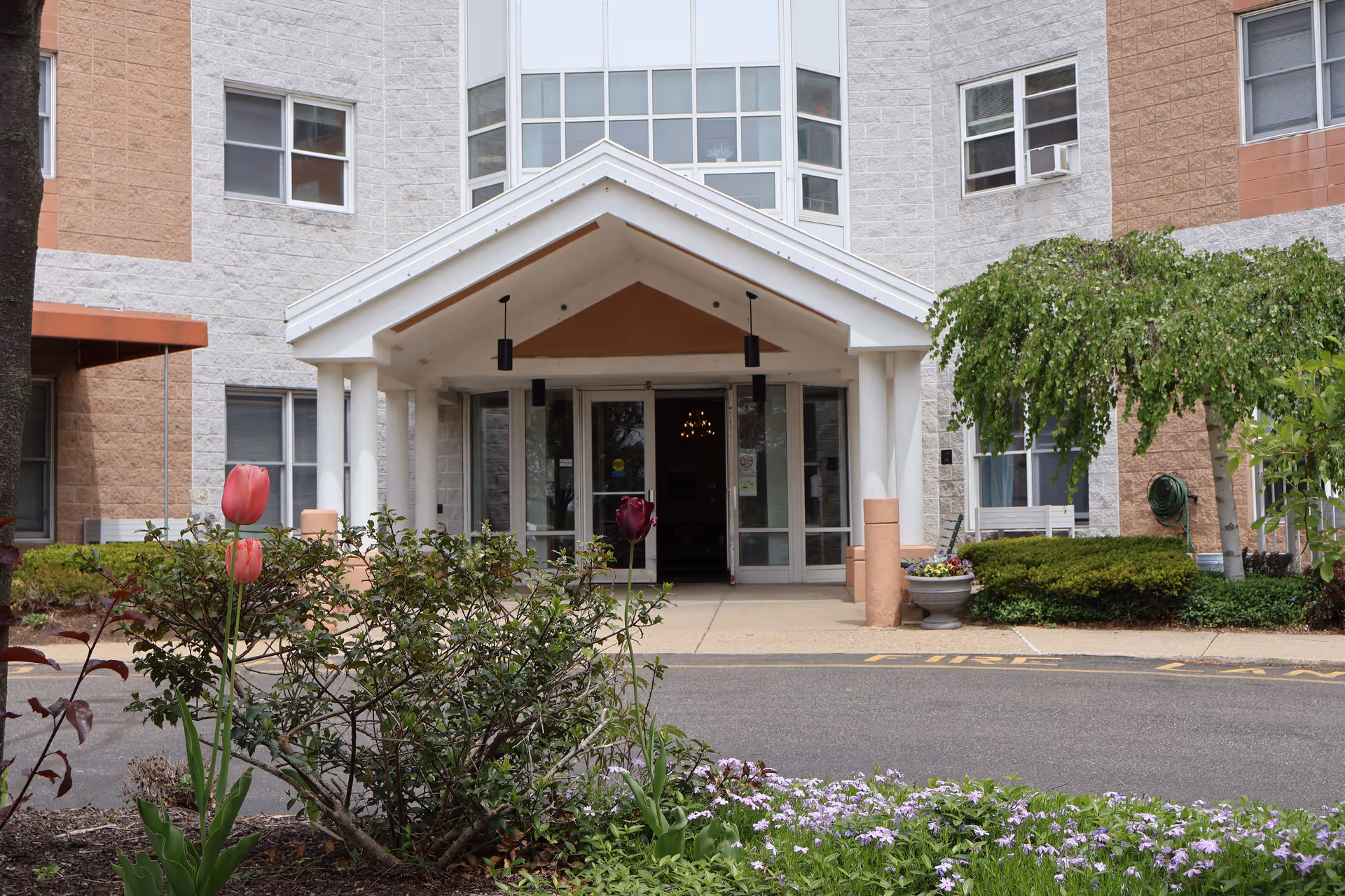 Front entrance of Oakland Grove Health Care Center with glass doors and landscaping.