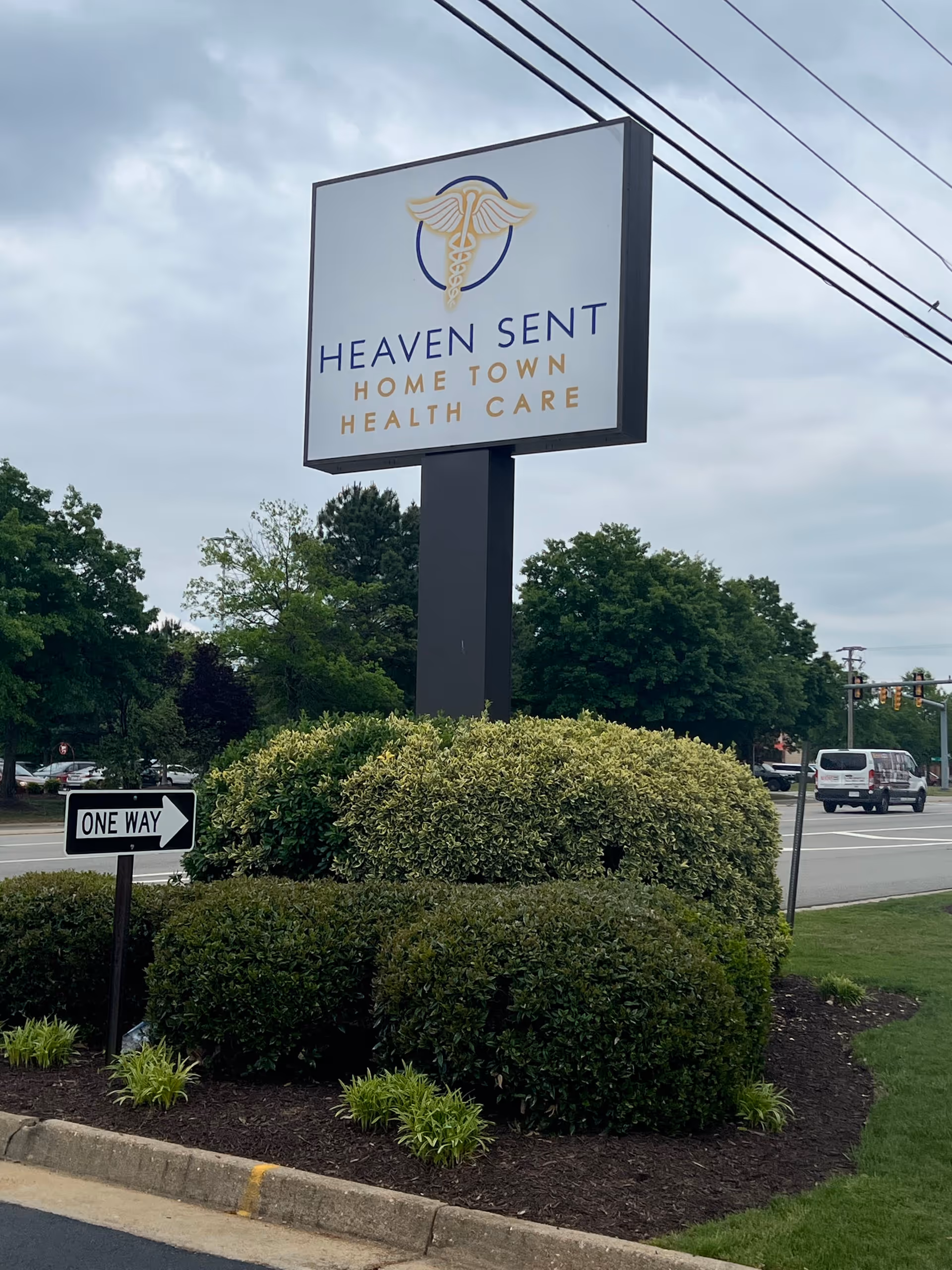 A tall sign reads Heaven Sent Home Town Health Care, surrounded by shrubs beside a roadway.