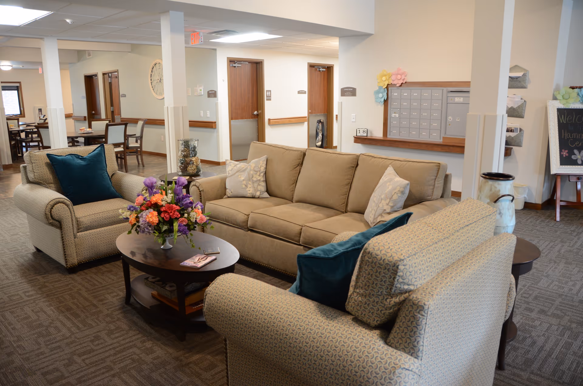 Cozy common lounge with beige sofas, coffee table, and flowers in Hammond Center.