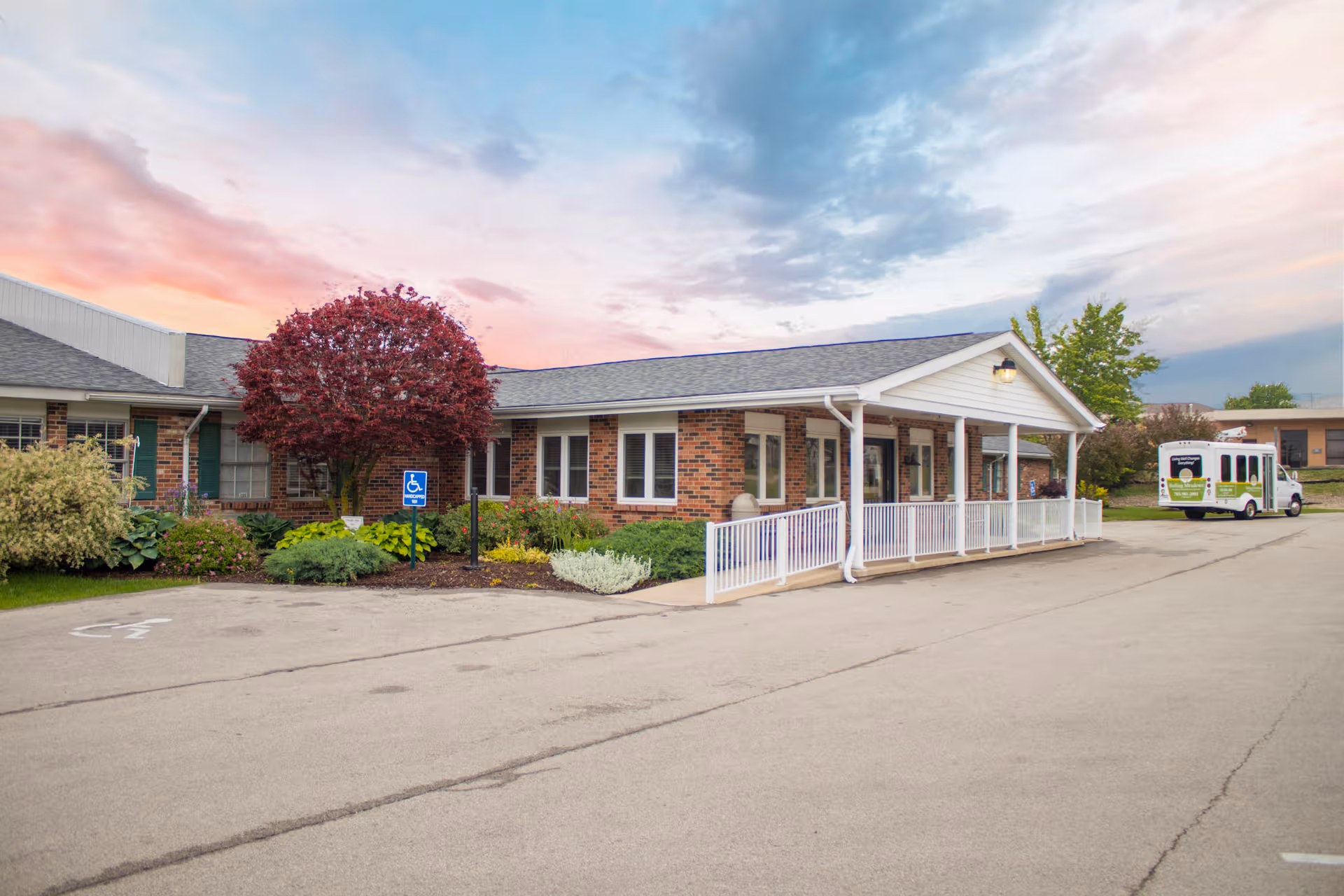 Front view of Rolling Meadows Health and Rehabilitation Center exterior with a covered entrance and bus.