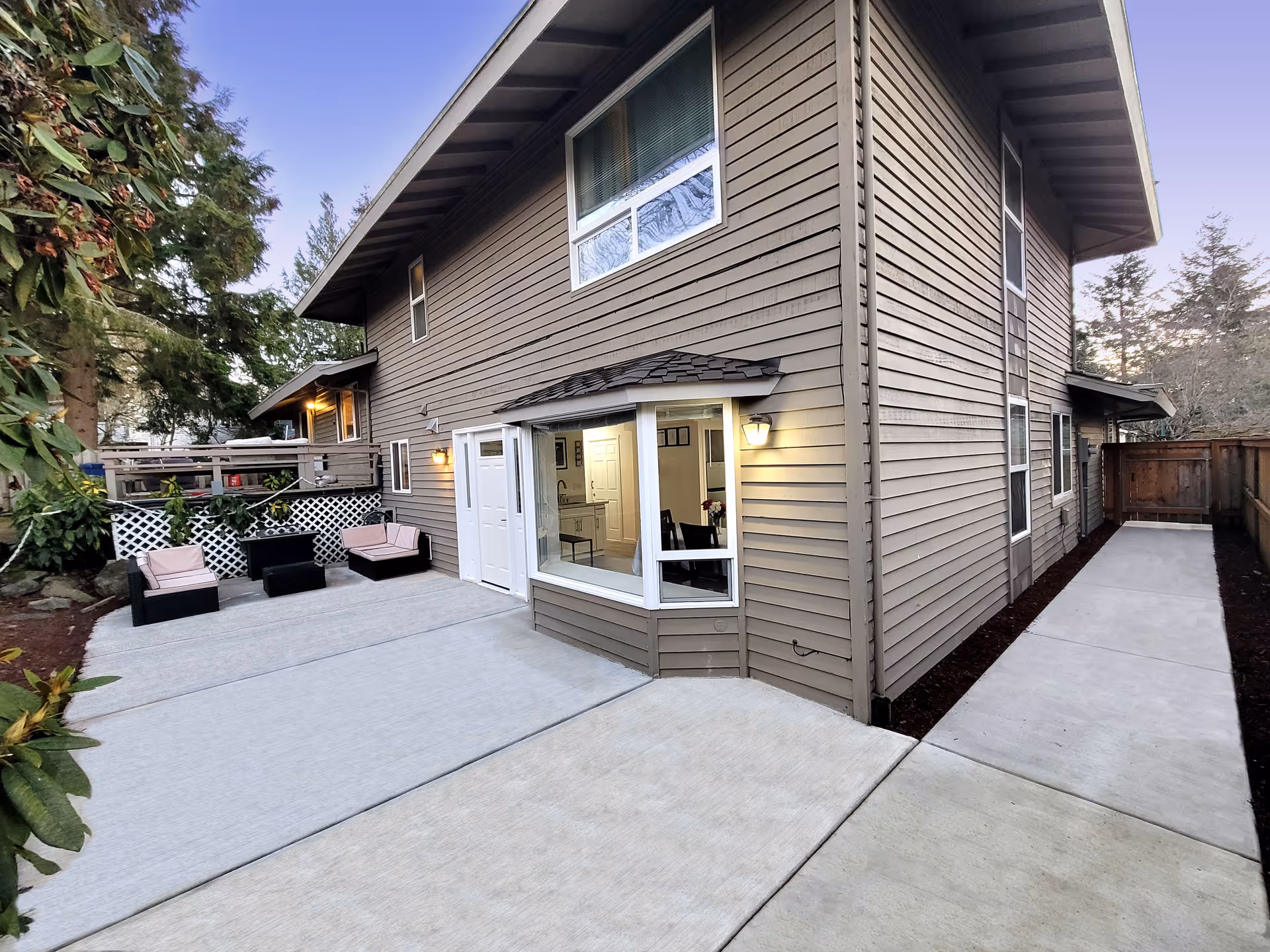 Two-story beige senior living home with a large outdoor patio and seating area.
