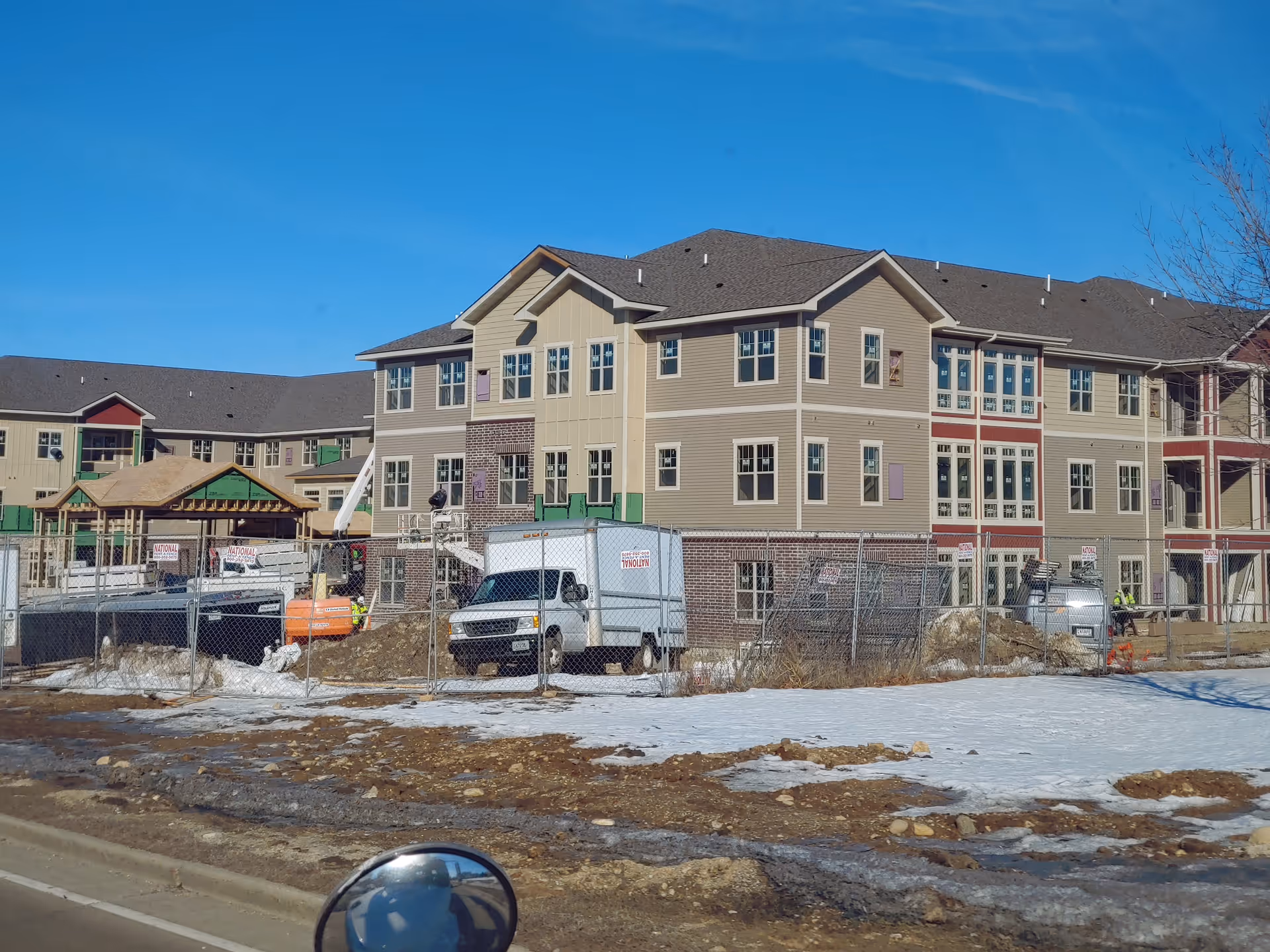 New Perspective Waukesha senior living building under construction, fenced, with trucks nearby.