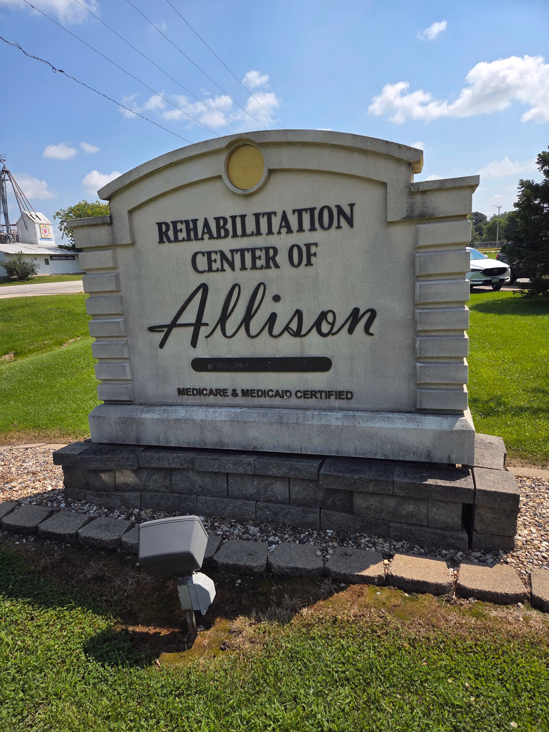 Stone rehabilitation center sign reading Allison on a grassy, sunny outdoor area.