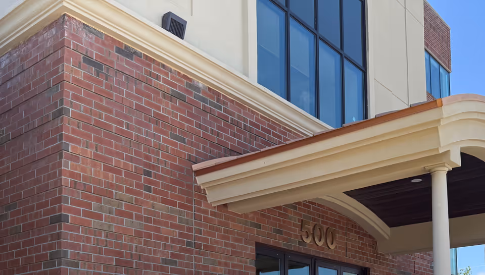 Brick exterior of a senior living facility with a covered entrance and large windows.