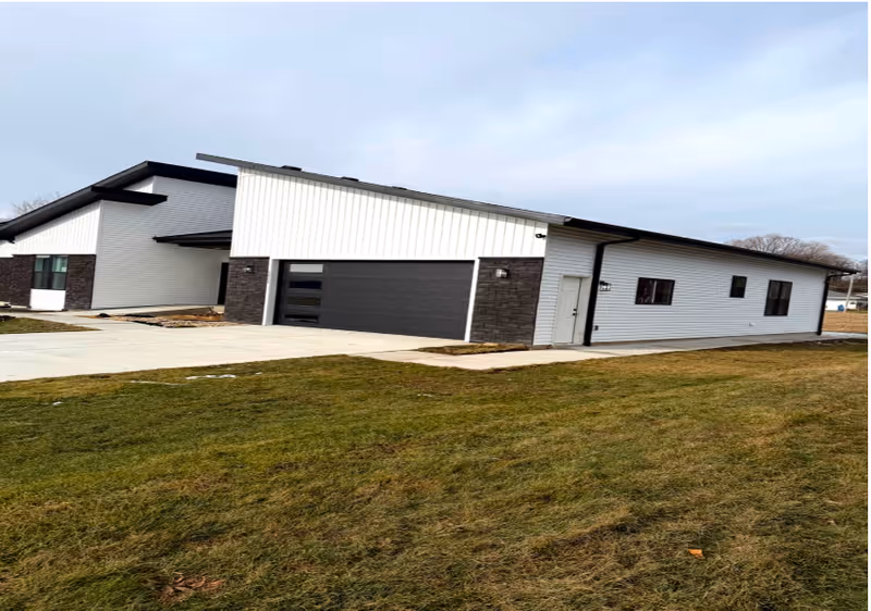 Modern single-story facility exterior with a two car garage and manicured lawn.