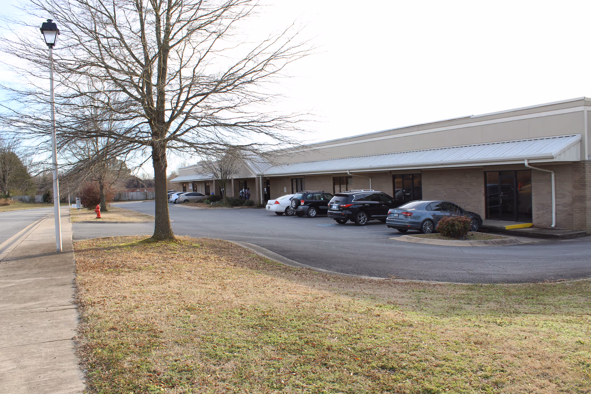 Exterior view of The Point Outpatient Behavioral Health Services (Conway) with parked cars and a tree.