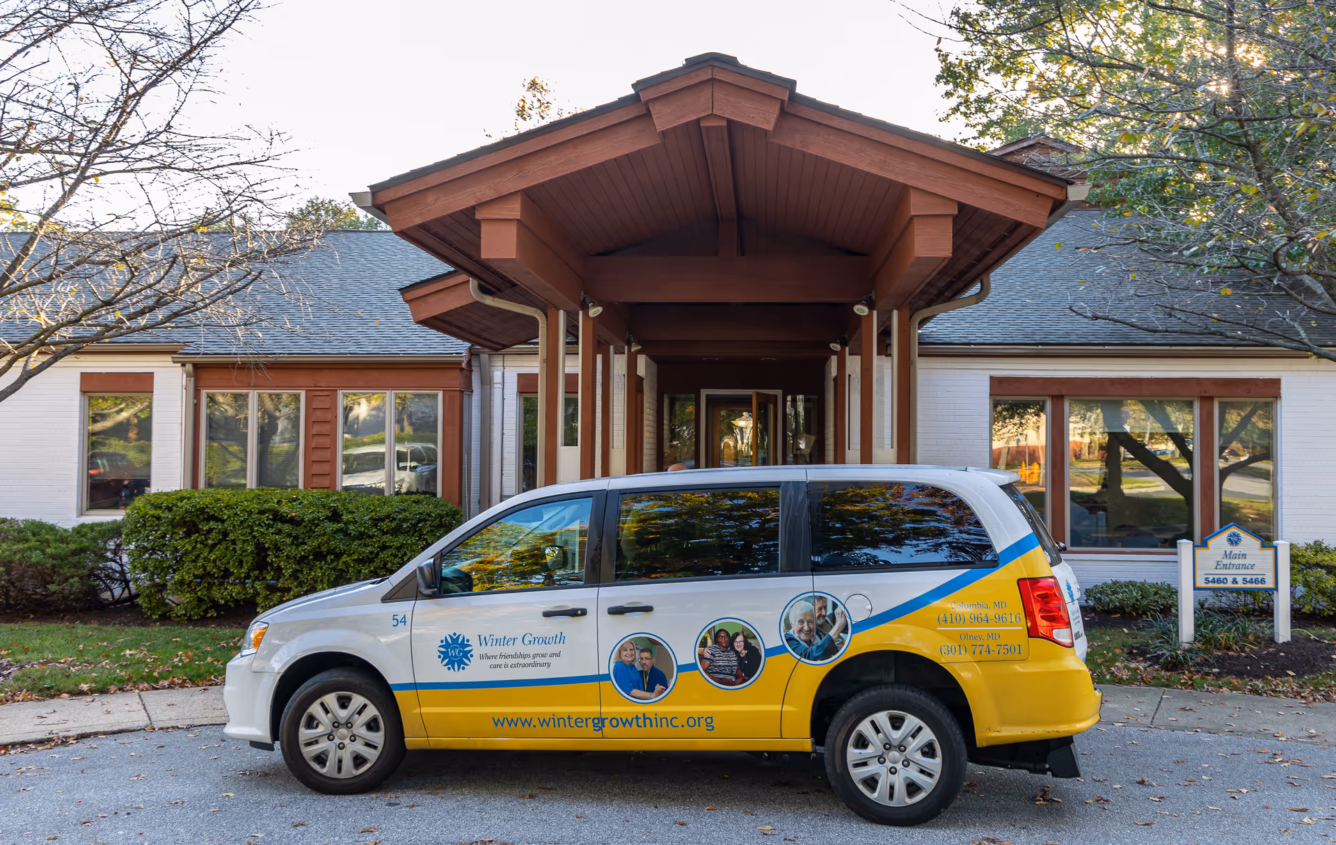 Front exterior of a Winter Growth senior living facility with a colorful shuttle van parked outside.