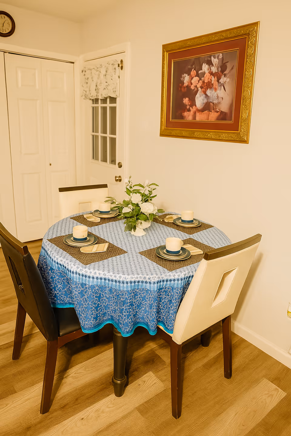 Round dining table with a blue patterned tablecloth and four place settings indoors.
