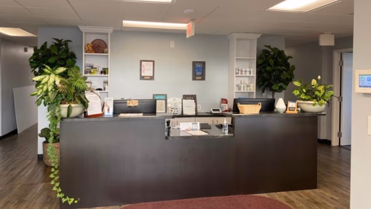 Reception desk in a modern facility lobby with plants, shelves, and a light blue wall.