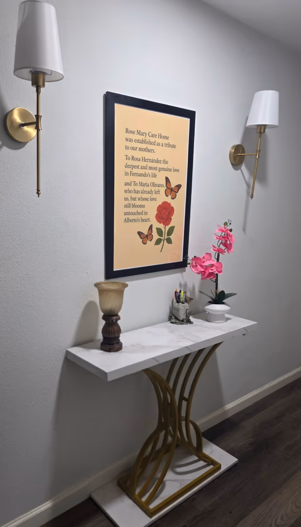 Interior hallway with a marble console table, framed art, and twin wall sconces.
