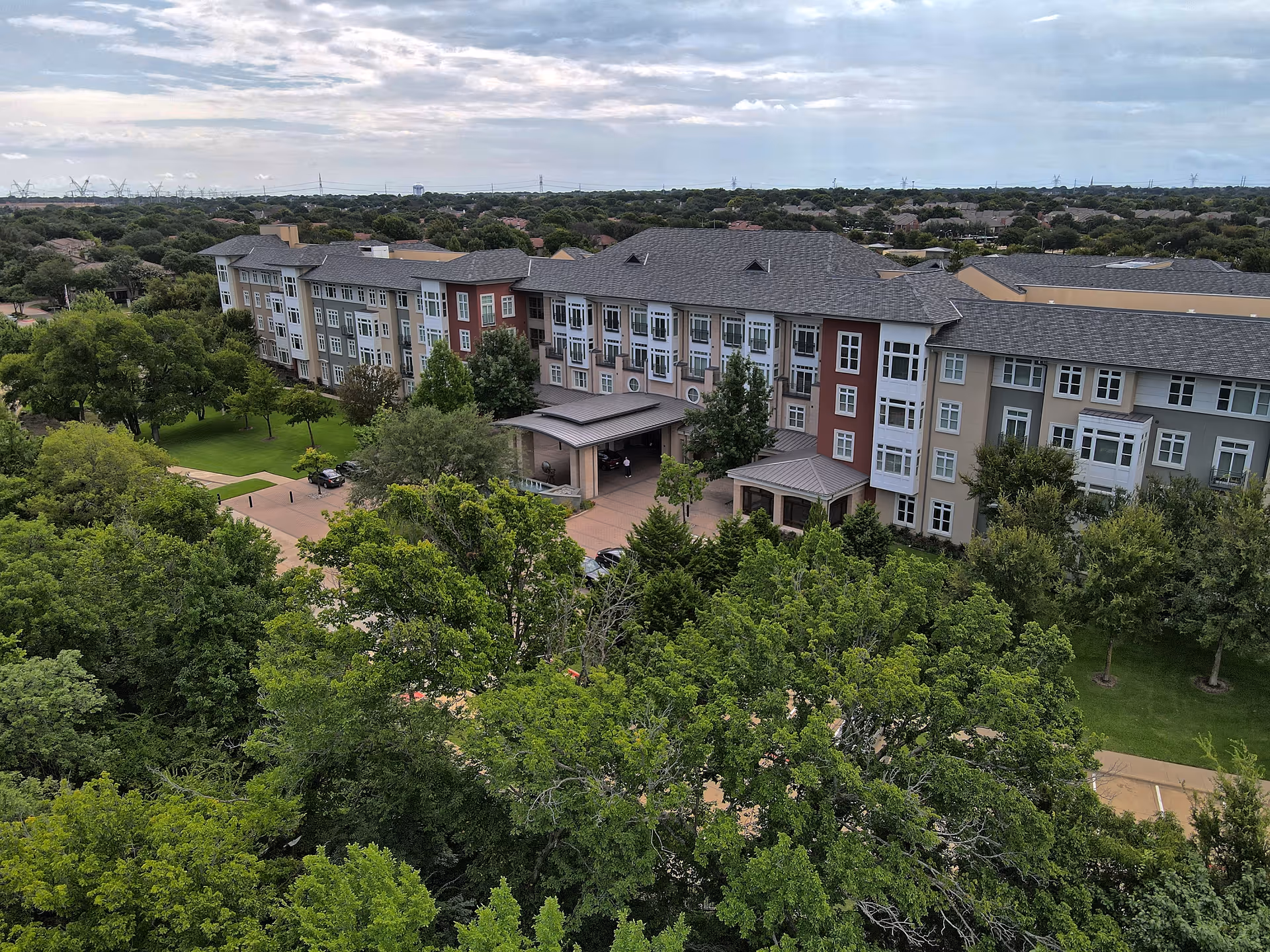 Aerial view of The Legacy Willow Bend senior living building with surrounding trees and parking.
