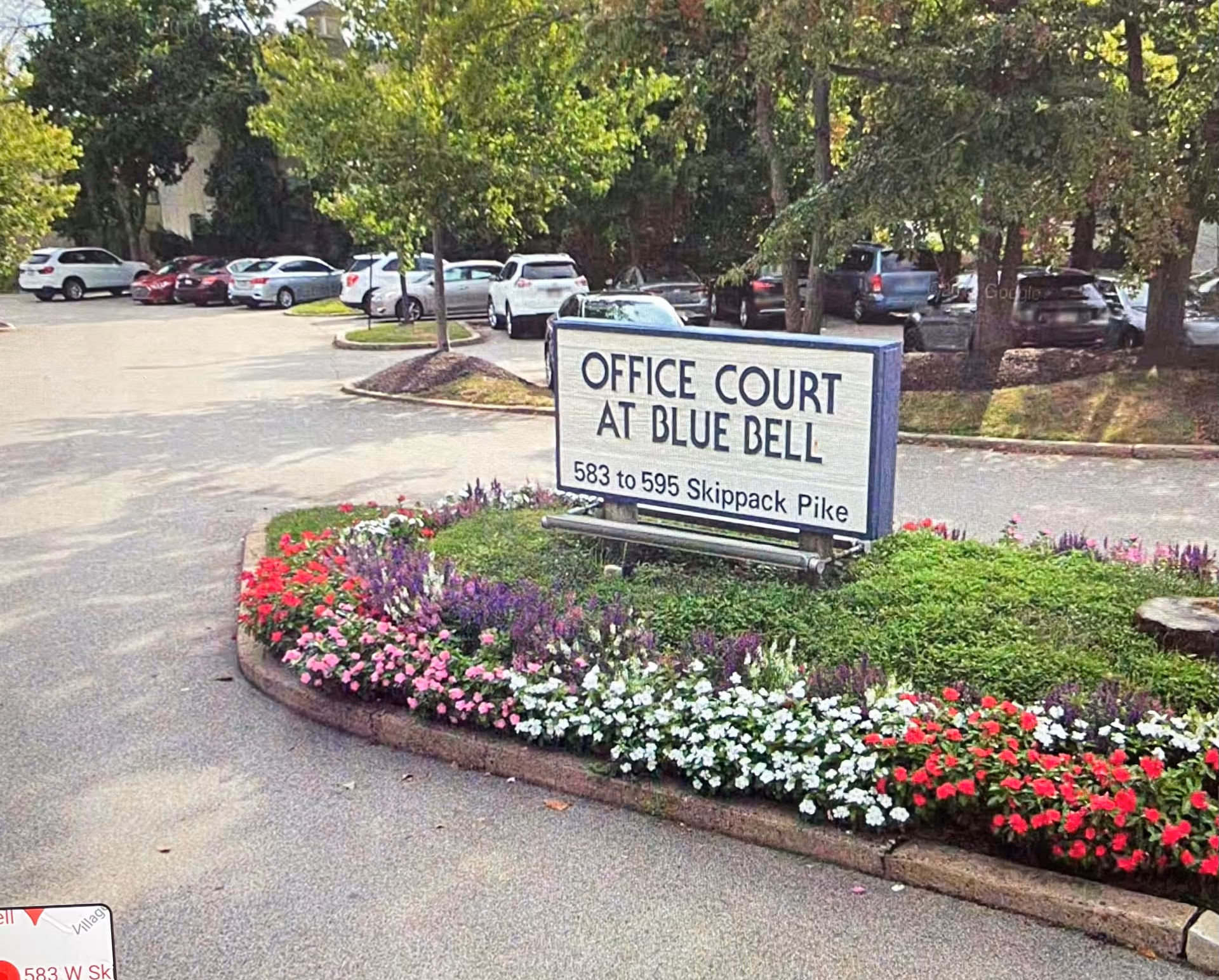 Sign for Office Court at Blue Bell surrounded by colorful flower beds.
