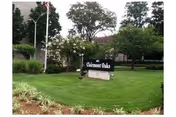 Well-maintained lawn with Clairmont Oaks sign and trees near a campus building.