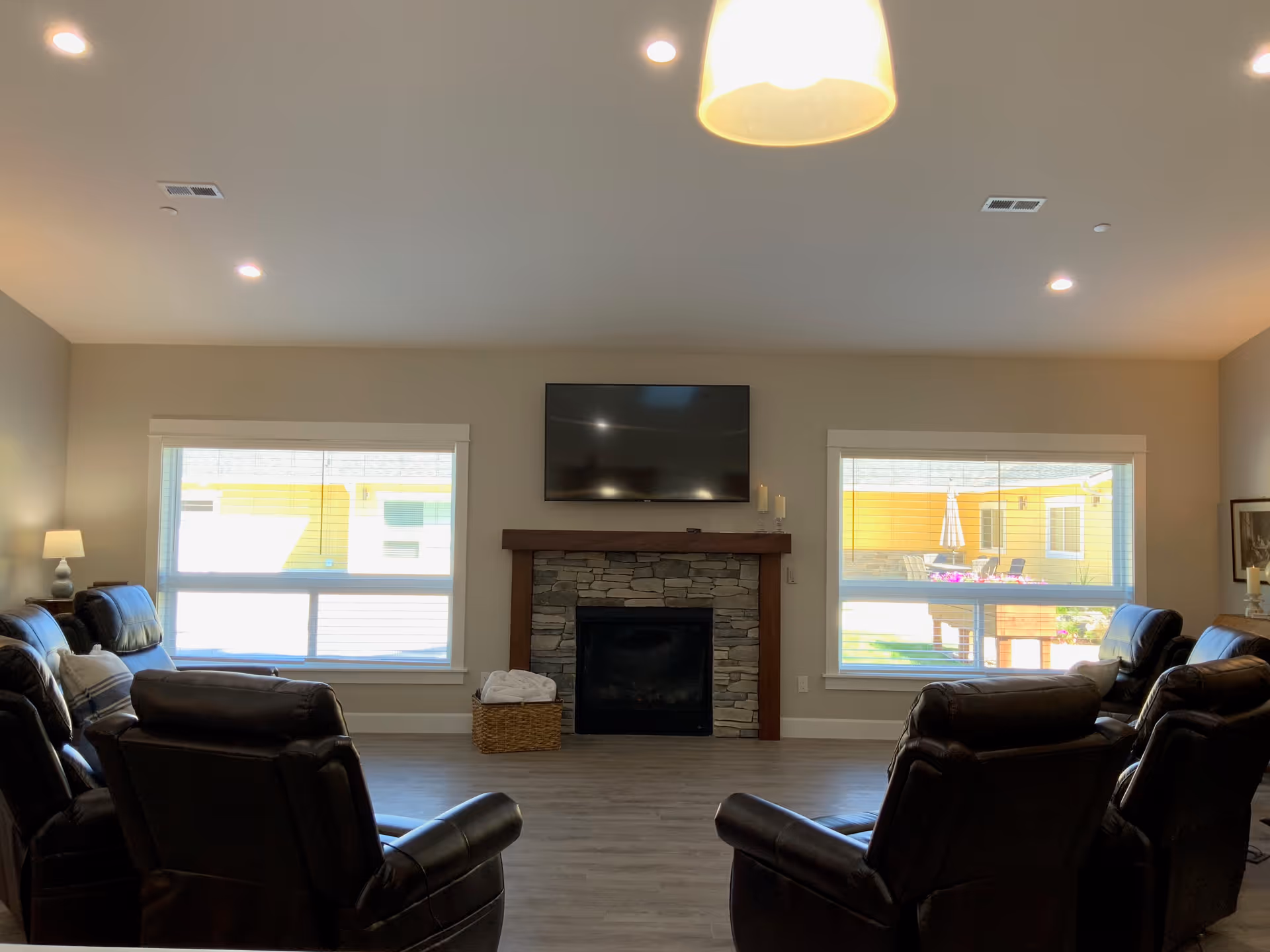 A spacious living room with recliners arranged around a stone fireplace and mounted TV.