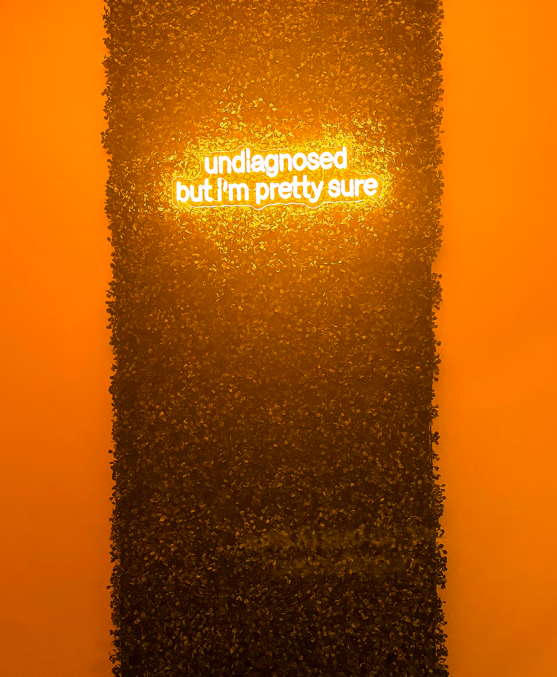 Orange-lit interior wall featuring a vertical garden and a glowing neon sign.
