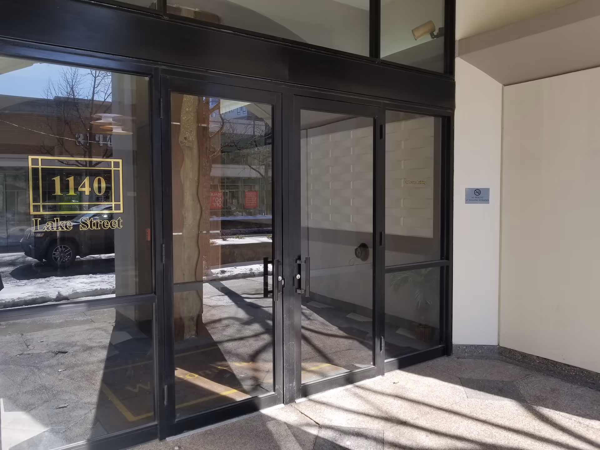Glass double doors frame a building entrance with a golden address plaque.