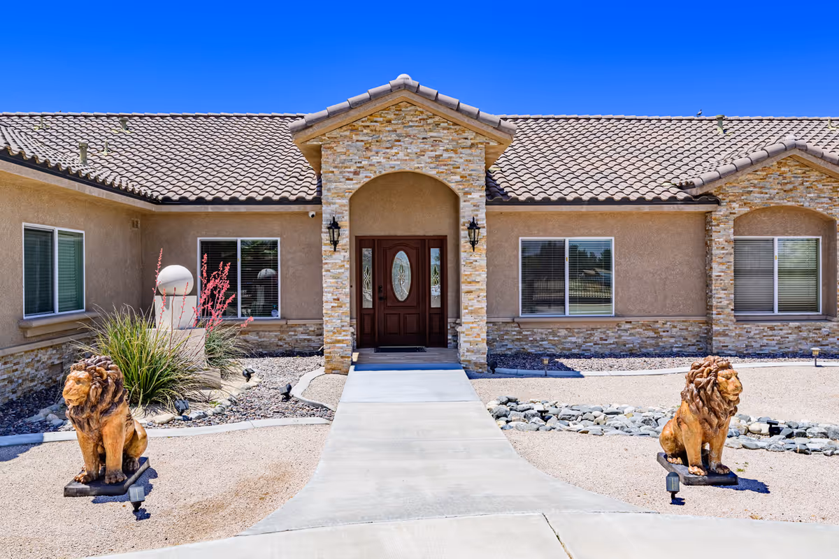 Front view of Palmdale Paradise Board & Care building with stone accents and lion statues.