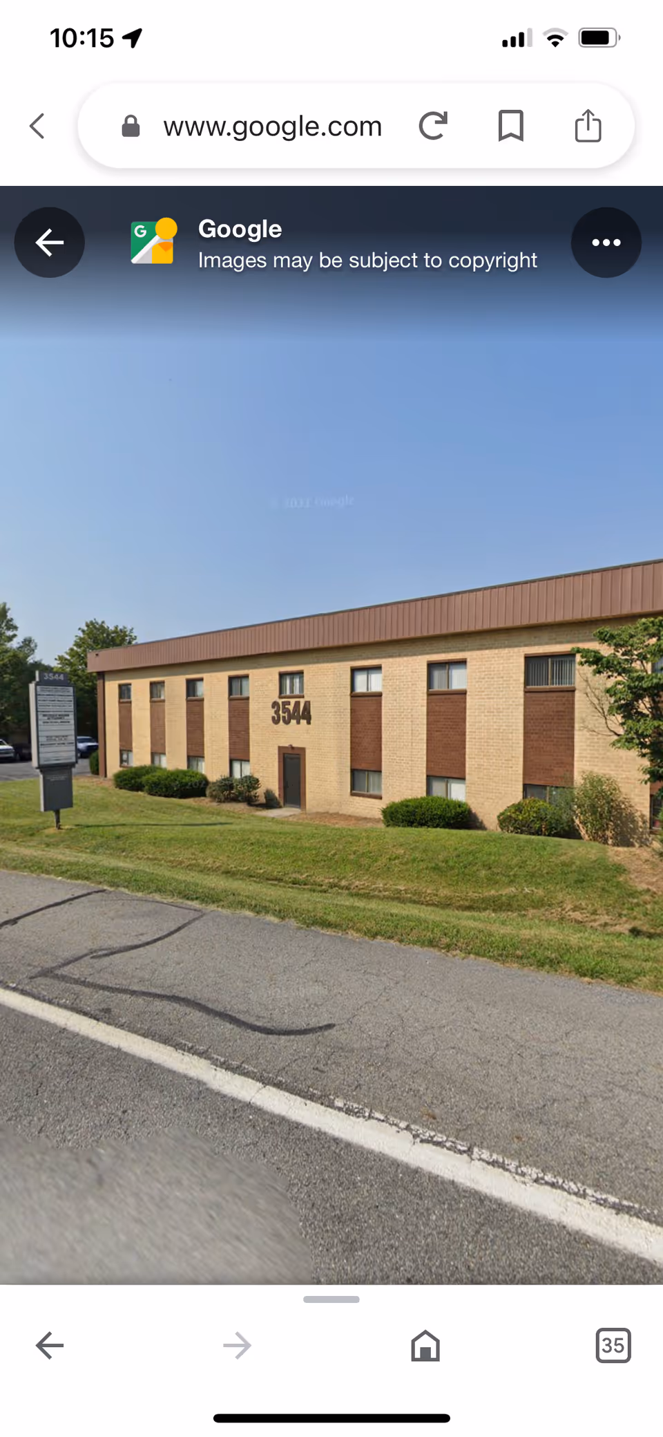 A brick two-story building with the number 3544 on the facade, set on a grassy lot.