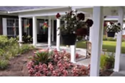 Exterior view of Baptist Village Lake Park with white columns and hanging flower baskets.