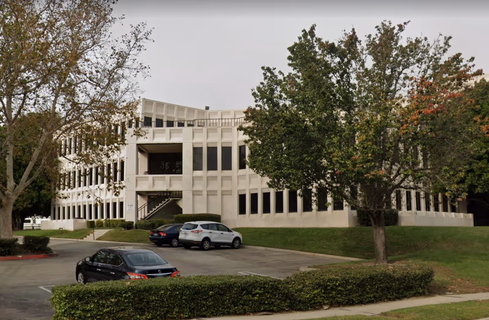 Exterior view of a white multi-story Khushy Senior Care building with parking.