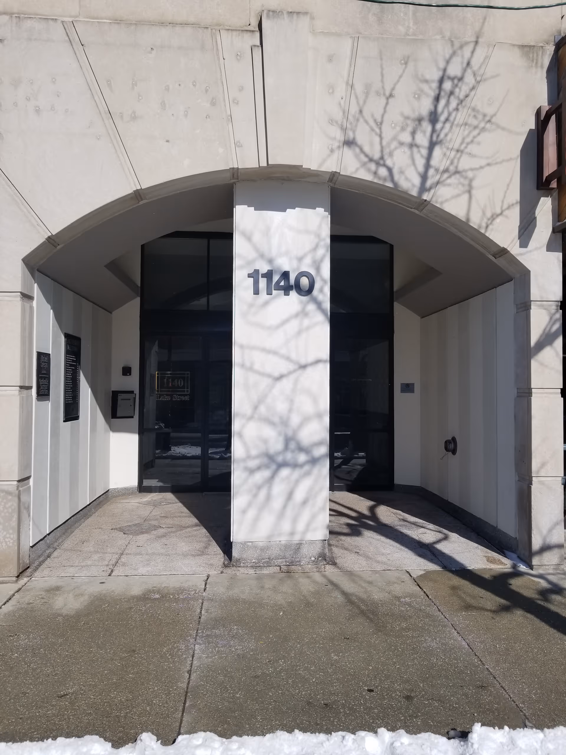 Front entrance of a building with an arch, glass doors, and the number 1140.