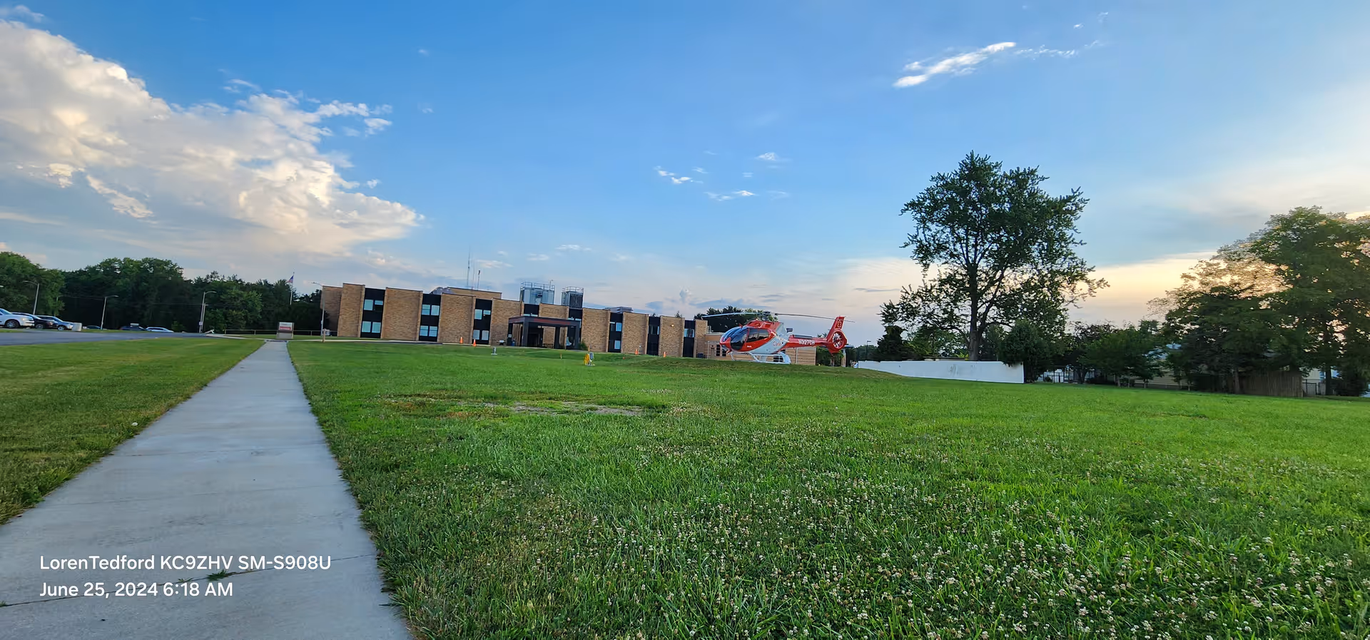 Wide exterior view of the hospital with a helicopter parked near the building.
