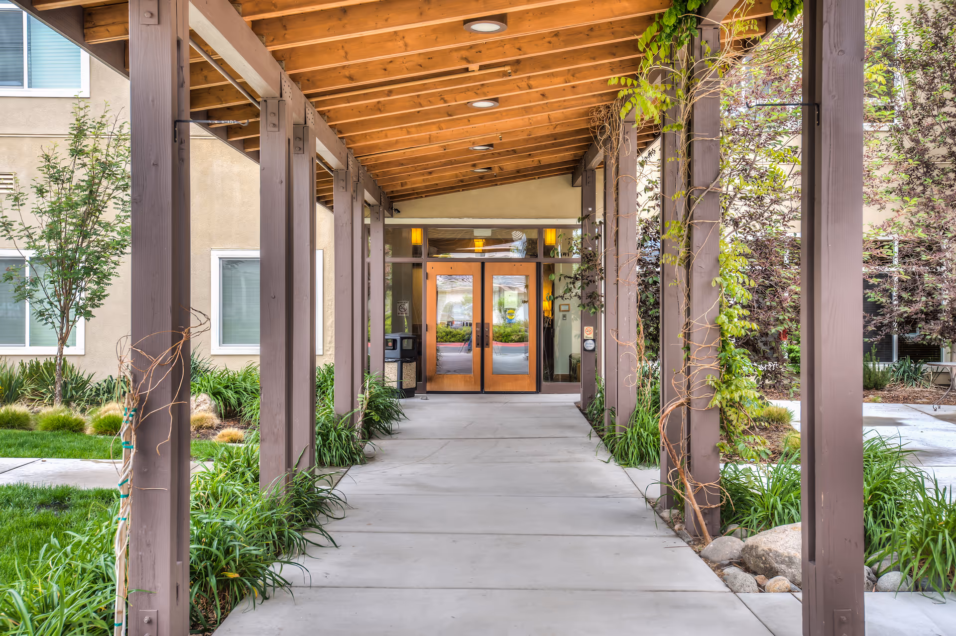 Covered wooden walkway leads to glass doors at The Lodge - Carson City.