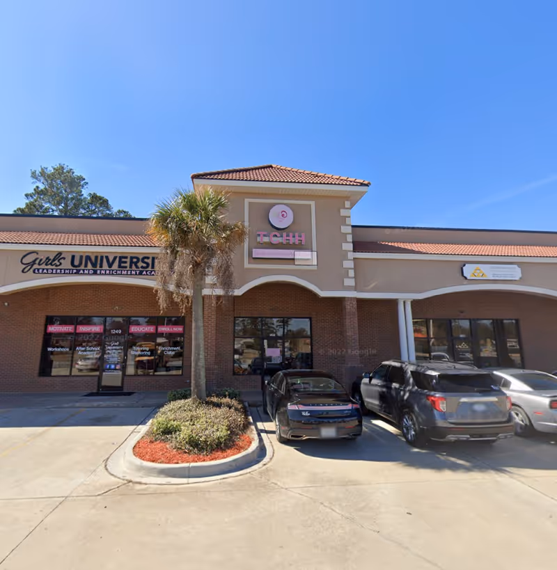 Exterior of a strip mall featuring Tender Care Home Health Services and parked cars.