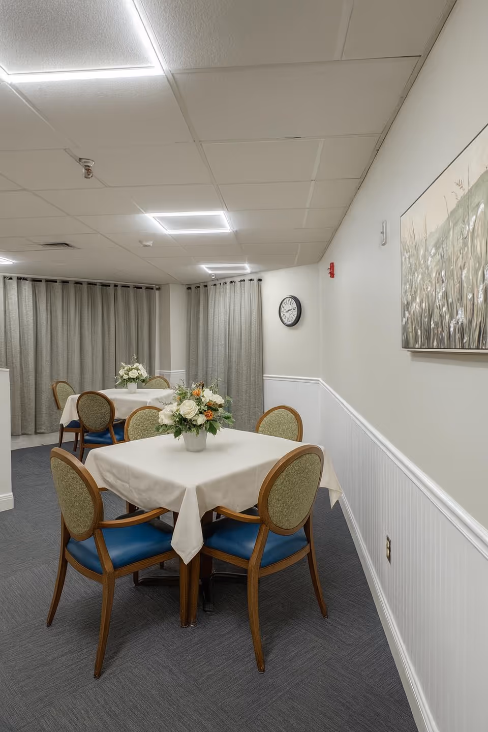 Parkview dining room with round tables, white linens, floral centerpieces, and blue-cushioned chairs.