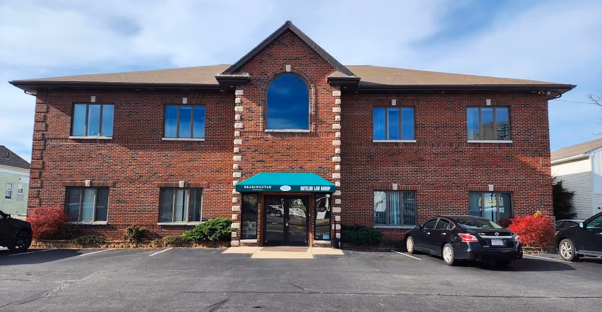 Two-story brick senior living facility with an arched central window and glass doors at the entrance.