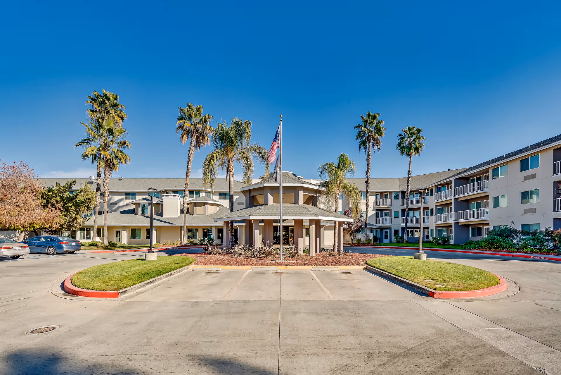 Exterior view of The Remington Senior Living with a central entrance and palm trees.