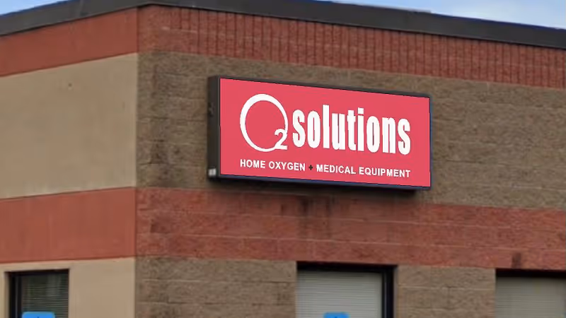 Exterior view of a brick building with a red Q Solutions medical equipment sign.
