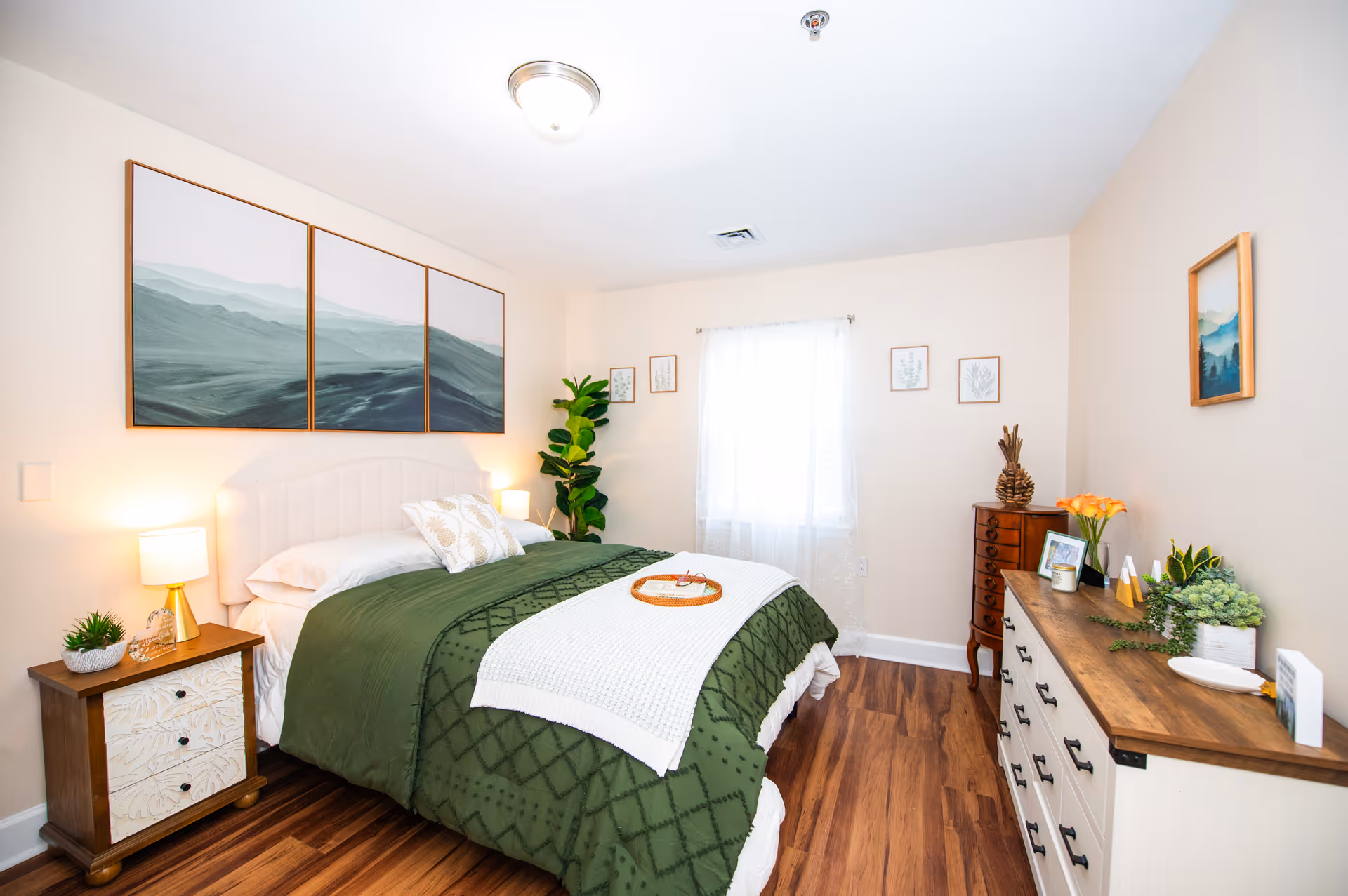 Cozy bedroom in a senior living facility with green bedding and wood furniture.
