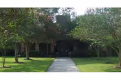 Pathway leads to Heritage Manor of Houma's entrance, framed by trees and a green lawn.