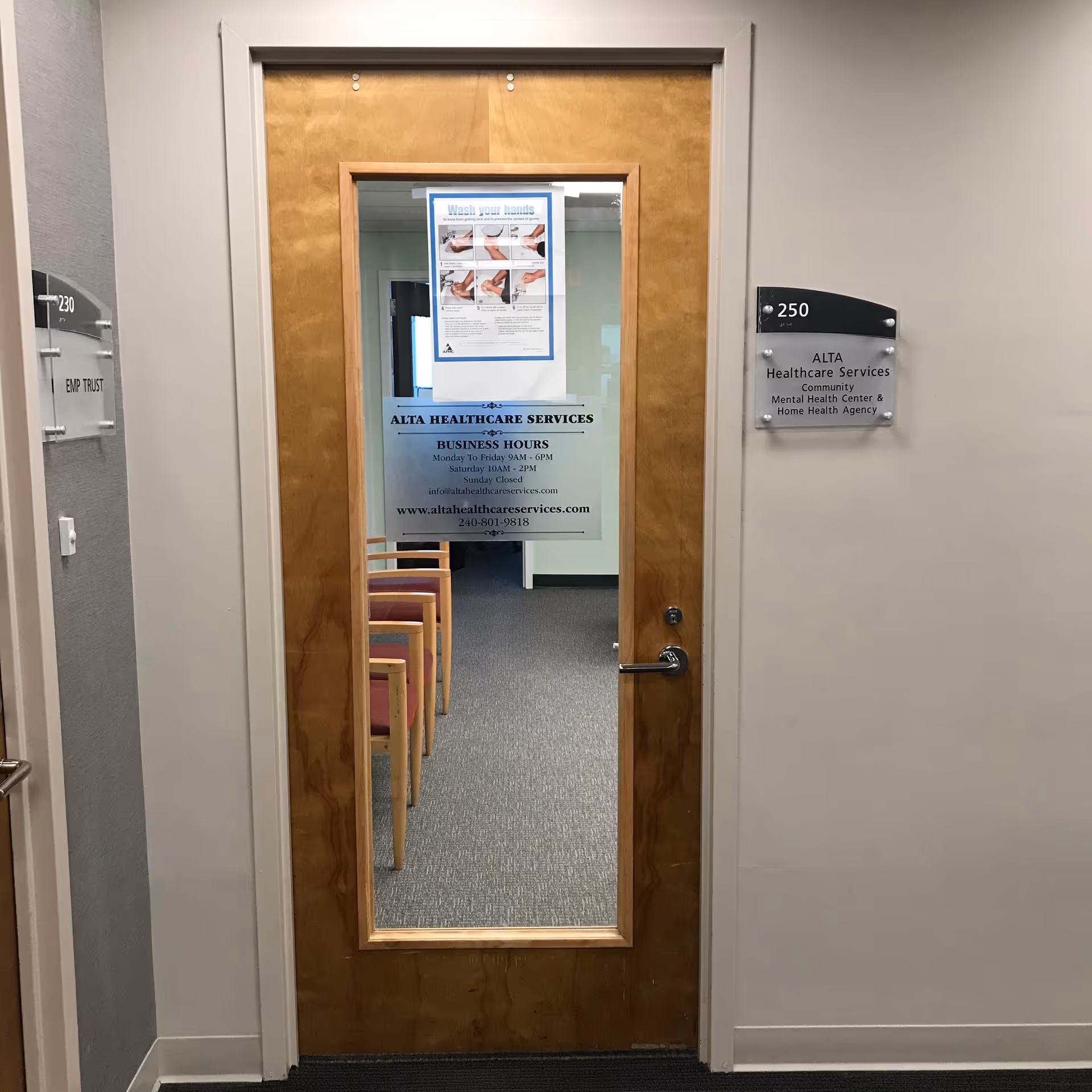Wooden door with glass panel leads to an interior hallway with chairs, Alta Healthcare Services sign.