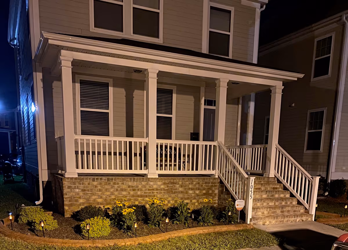 Two-story beige senior living building with covered front porch and staircases at night.