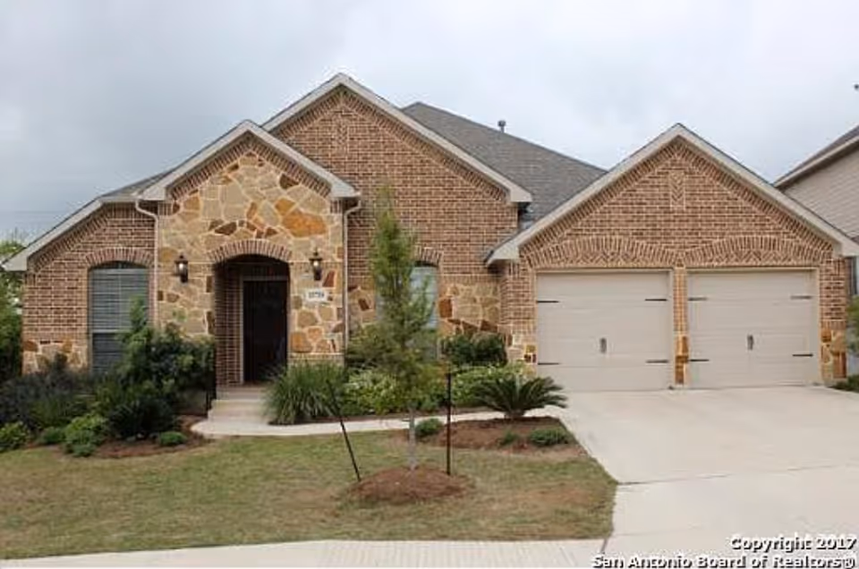 Brick-and-stone single-story house with a two-car garage, front lawn, and driveway.