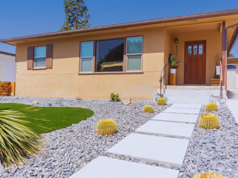 Front of a single-story assisted living home with a stone walkway and desert landscaping.