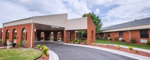 Brick senior living facility with a covered entrance and manicured landscaping.