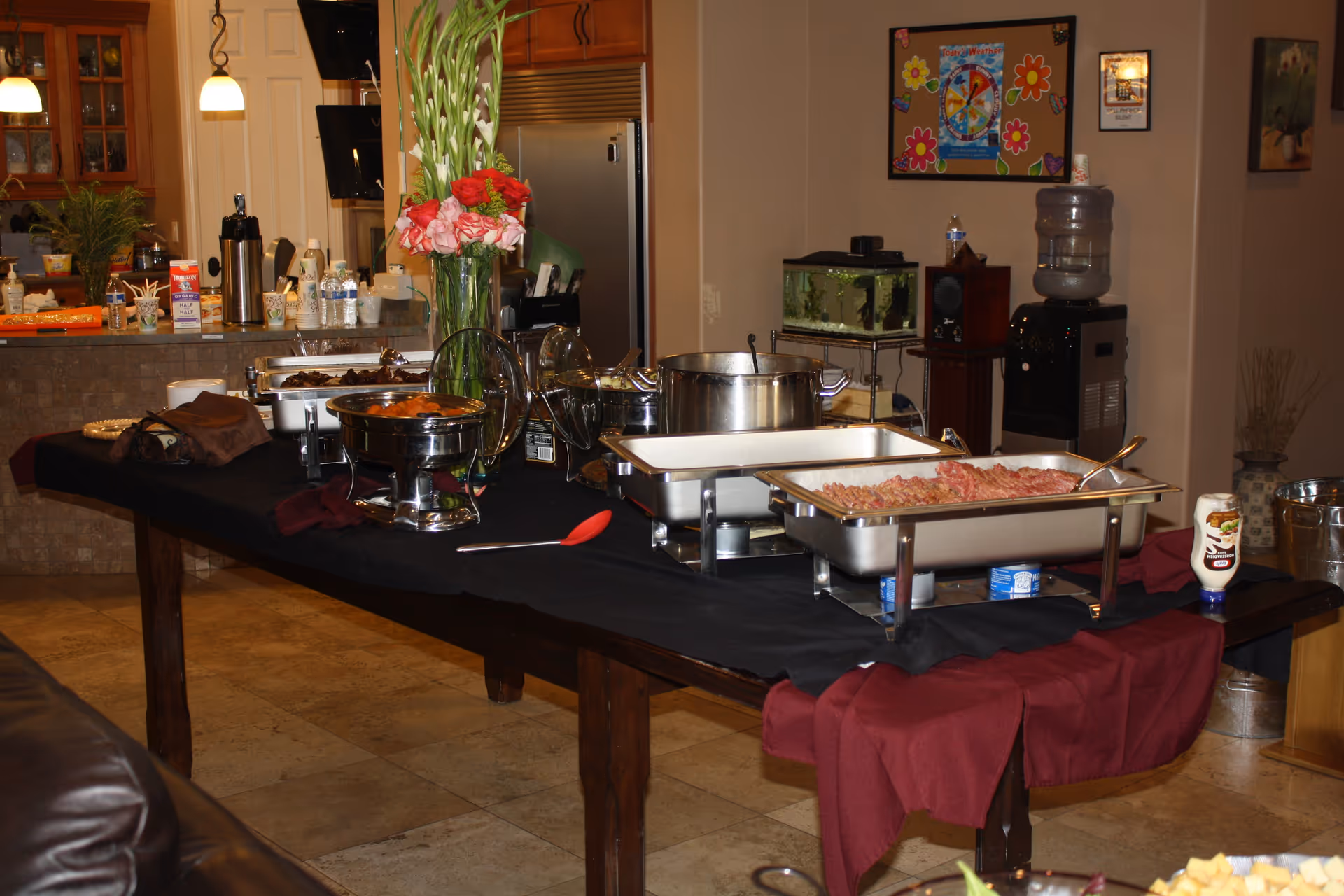Buffet table with chafing dishes in a senior living facility dining area.
