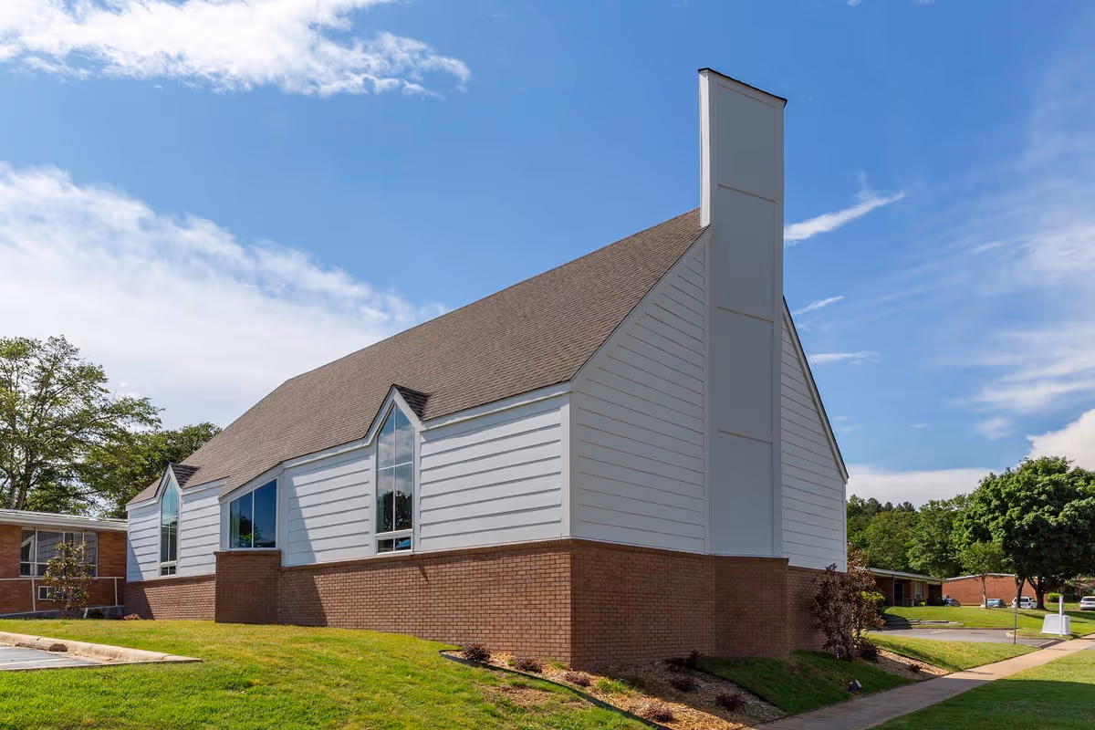 Exterior view of Presbyterian Village building with white siding and brick foundation.