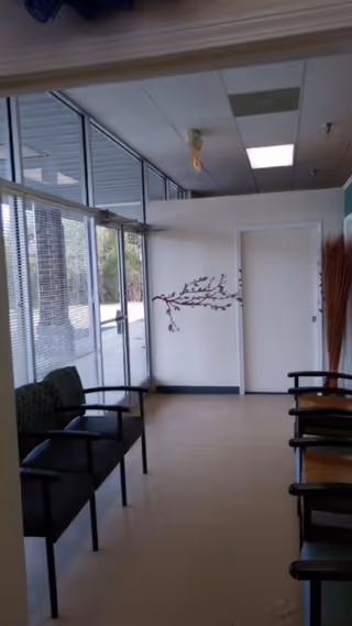 Interior hallway in a senior facility with seating along glass windows.