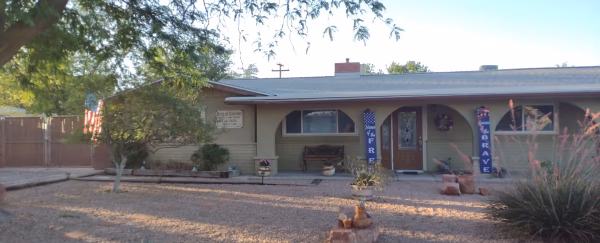 Single-story beige building with a front porch, decorative banners, and desert landscaping.