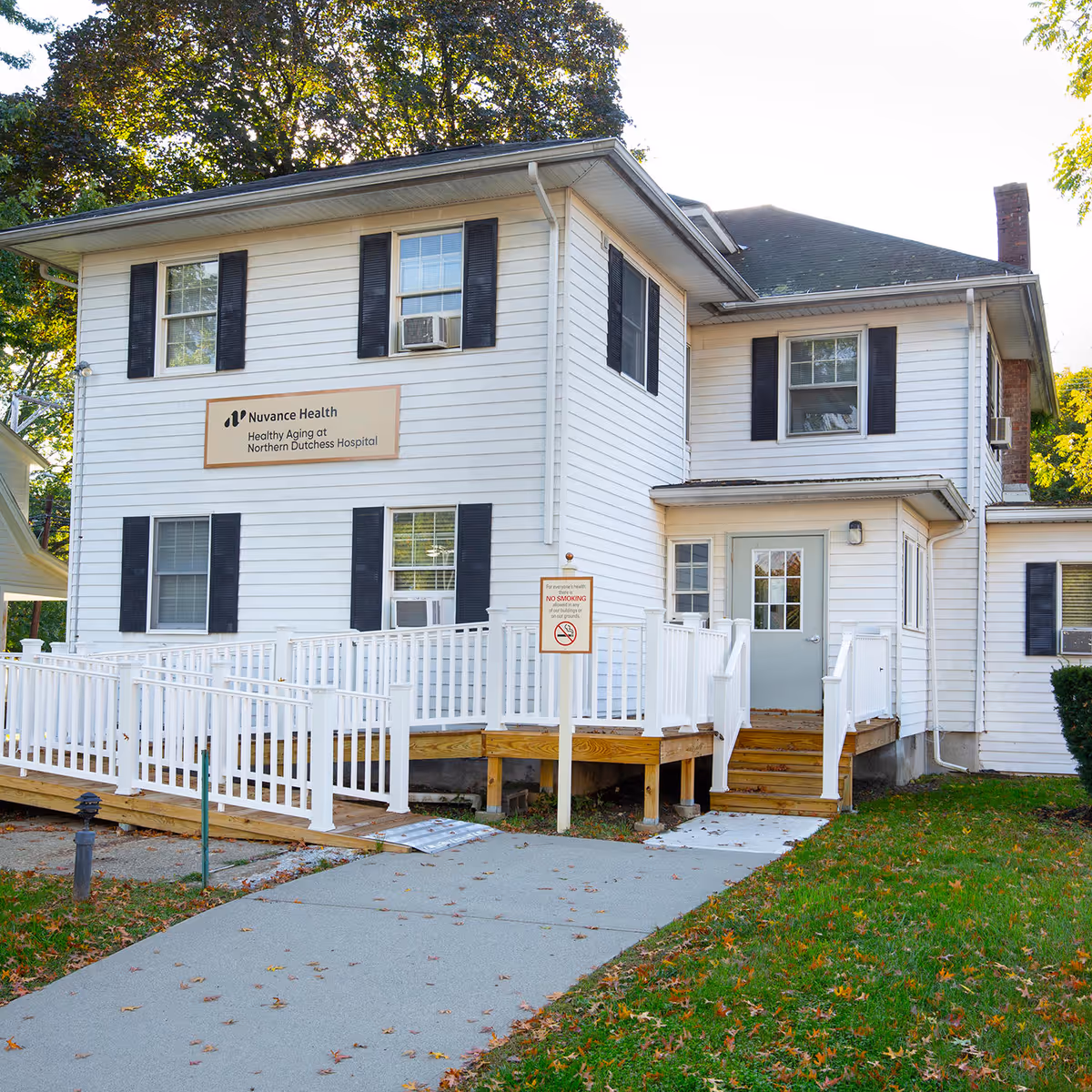 Two-story white building with sign, front entrance, and white railing ramp.