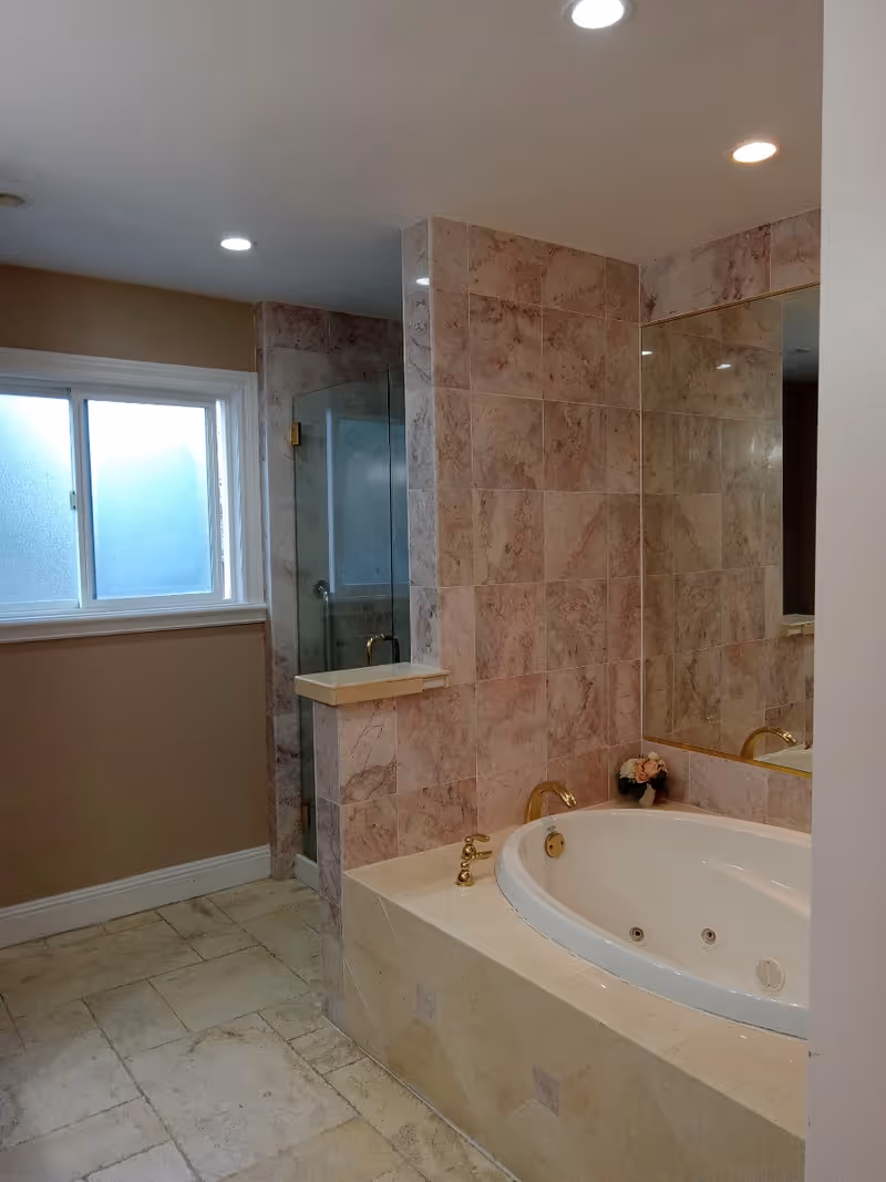 Spacious bathroom with a large marble tub, shower enclosure, and tiled walls.