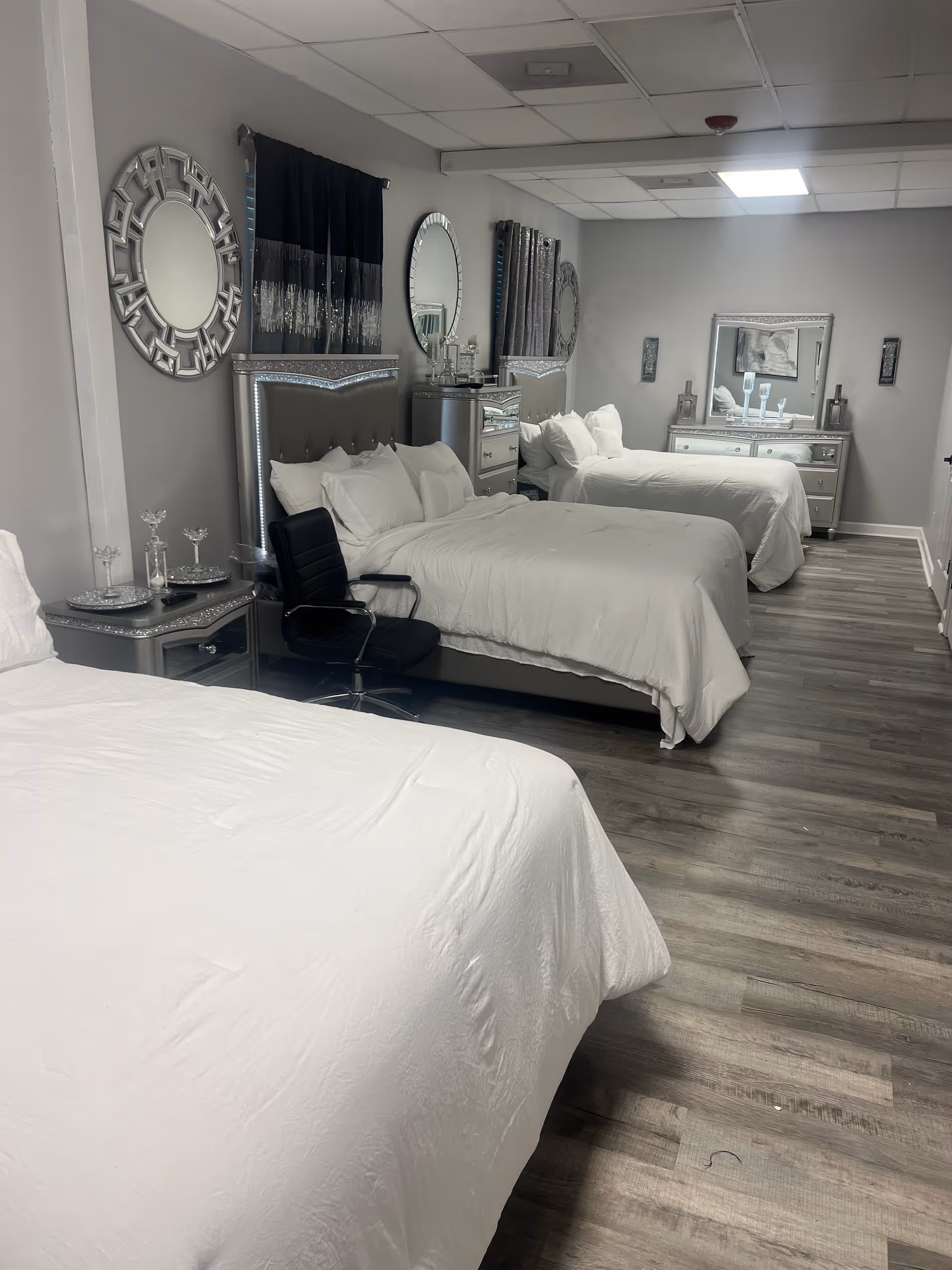 Shared bedroom suite with white bedding, silver headboards, and decorative mirrors along the wall.